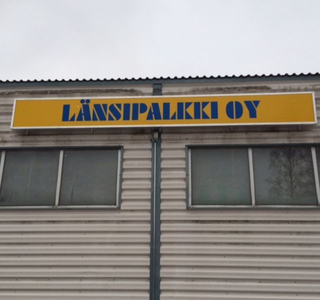 Keltainen Länsipalkki Oy -valomainos katonrajassa.